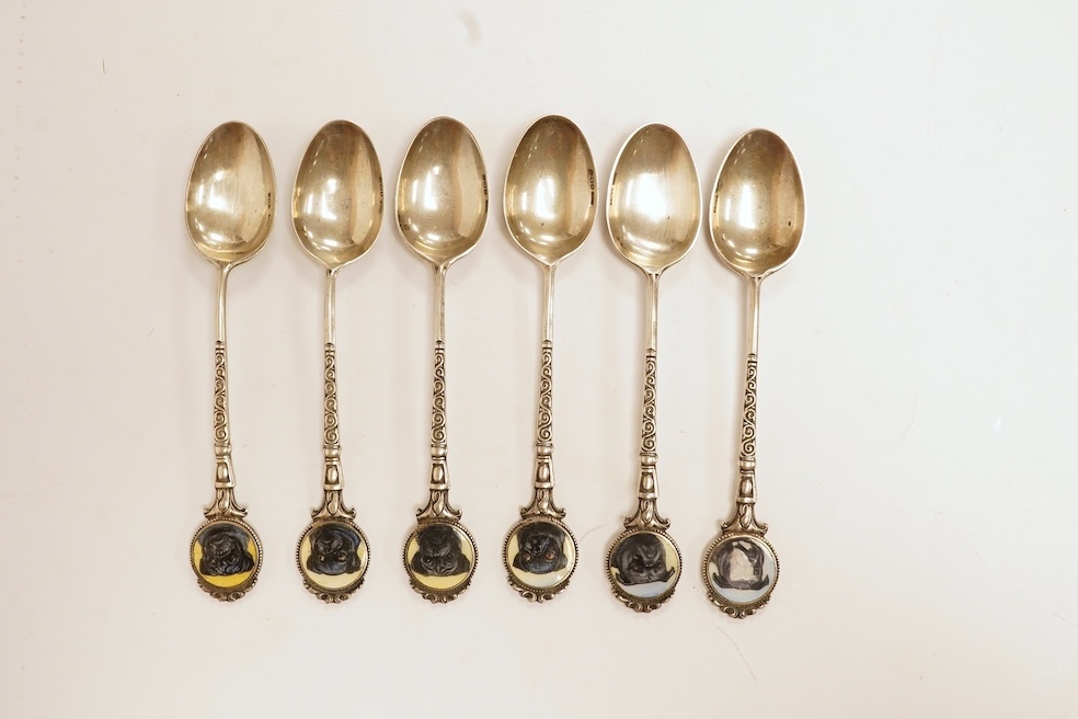 A matched set of six mainly George V silver/white metal and enamel teaspoons, with terminals decorated with dog's heads, 13.6cm. Condition - fair